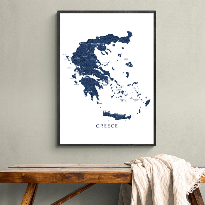 Framed map of Greece on a wall above a wooden bench.