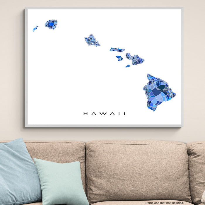 Framed map of Hawaii with blue mosaic design on a wall above a beige sofa.