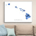 Framed map of Hawaii with blue mosaic design on a wall above a beige sofa.
