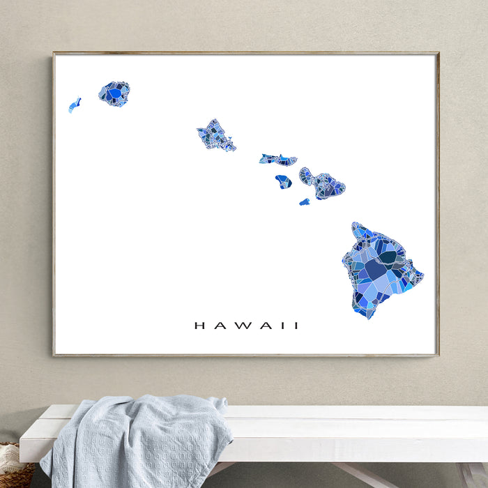 Framed map of Hawaii with blue mosaic design on a wall above a white bench.