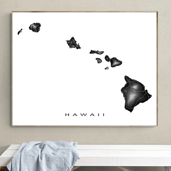 Framed black and white map of Hawaii on a wall above a white bench.