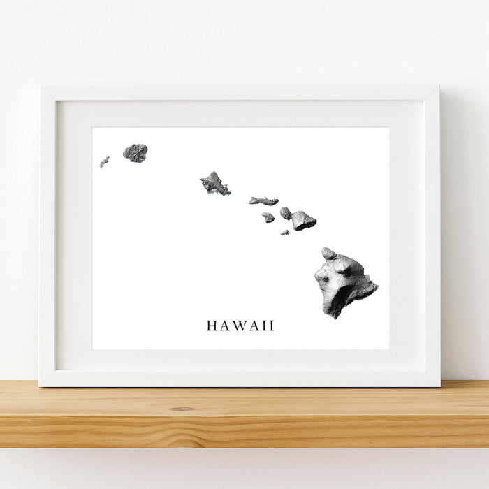 Framed artwork of a map of Hawaii on a white wall.