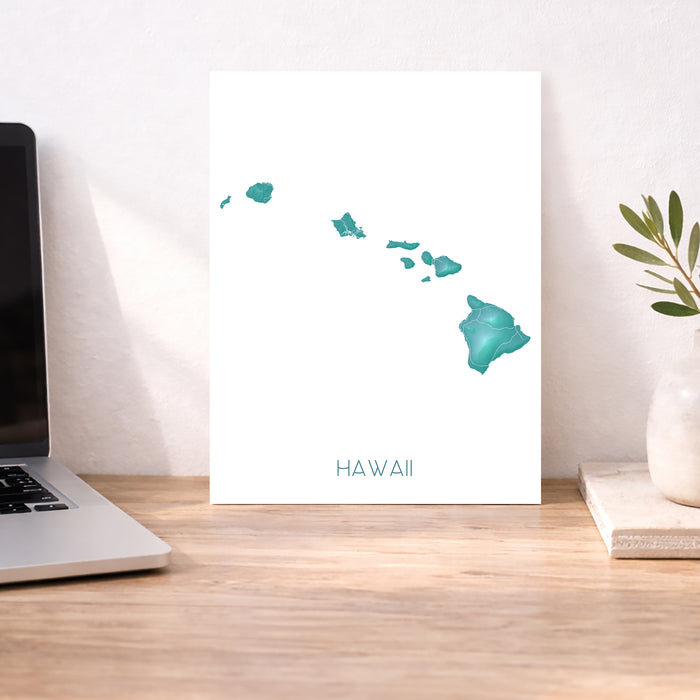 Desk with a laptop, a print of Hawaii, and decorative items.