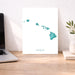 Desk with a laptop, a print of Hawaii, and decorative items.
