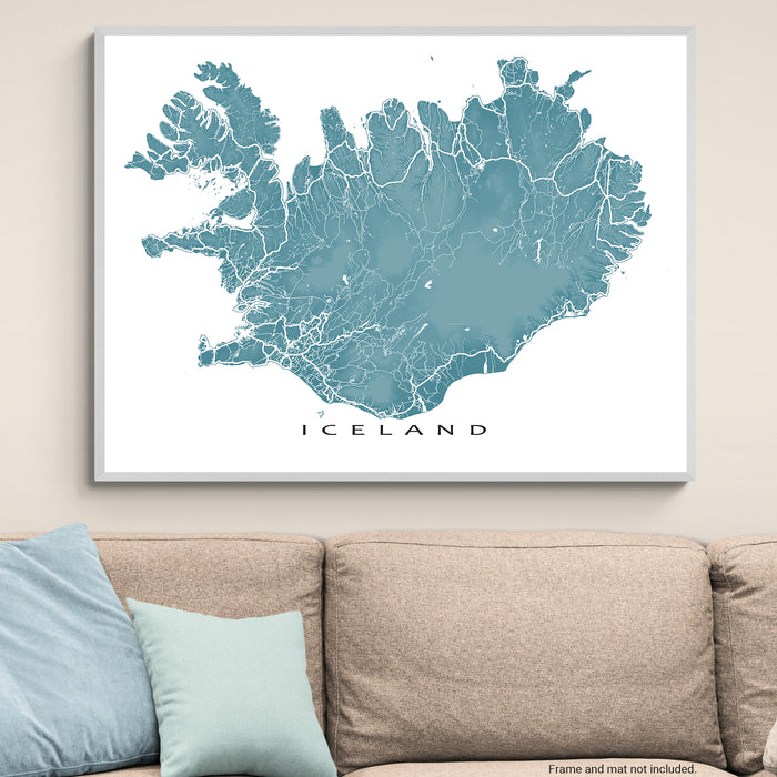 Framed map of Iceland on a wall above a beige sofa with light blue cushions.