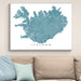 Framed map of Iceland on a wall above a beige sofa with light blue cushions.