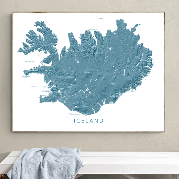 Framed map of Iceland on a wall above a white bench.