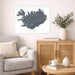 Living room with a framed map of Iceland on the wall, a beige sofa, wooden cabinet, and small table with decor items.