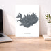 Map of Iceland on a white background next to a laptop on a wooden desk.