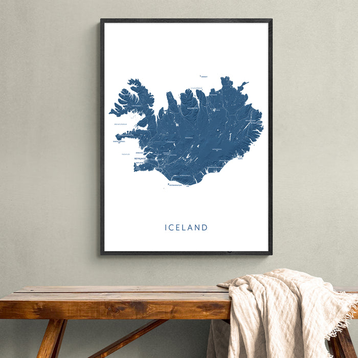 Framed map of Iceland on a wall above a wooden bench.