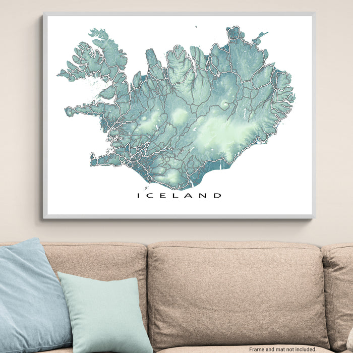 Framed map of Iceland on a wall above a sofa with light blue cushions.