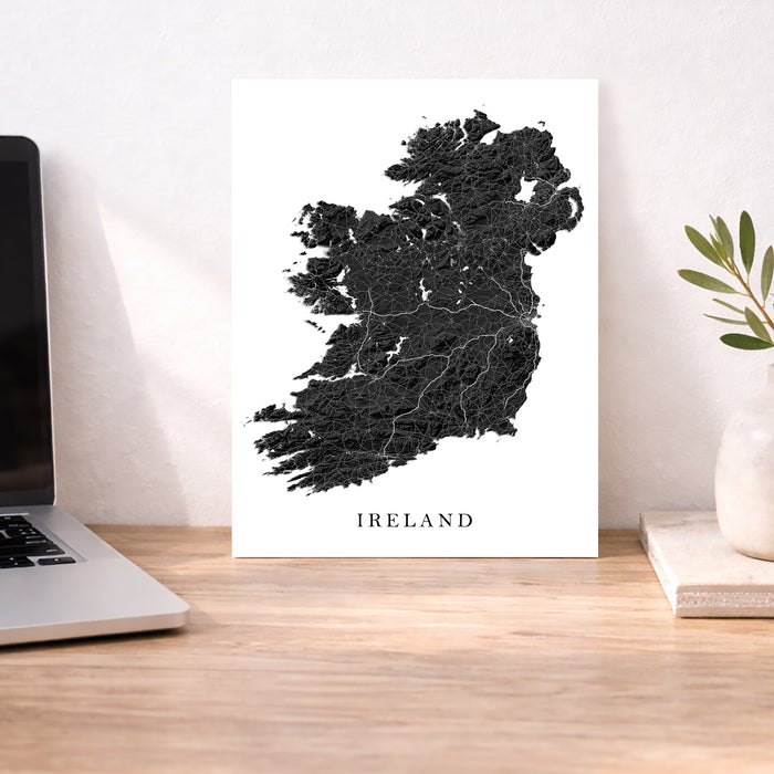 Map of Ireland on a white background next to a laptop on a wooden desk.