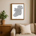 Framed map of Ireland on a wall above a beige sofa with a plant beside it.