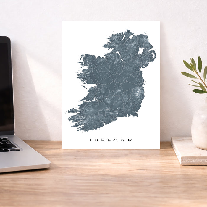 Map of Ireland on a white background next to a laptop on a wooden desk.