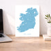 Map of Ireland on a white background next to a laptop on a wooden desk.
