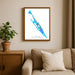 Framed map of Isla Mujeres on a wall above a beige sofa with a plant beside it.