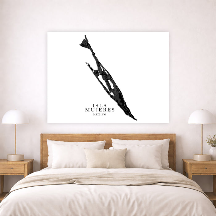 Framed artwork of a silhouette of Isla Mujeres, Mexico on a wall above a bed.