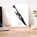 Poster of a silhouette with 'Isla Mujeres, Mexico' text on a desk with a laptop and plant.