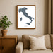 Framed map of Italy on a wall above a beige sofa with a plant beside it.