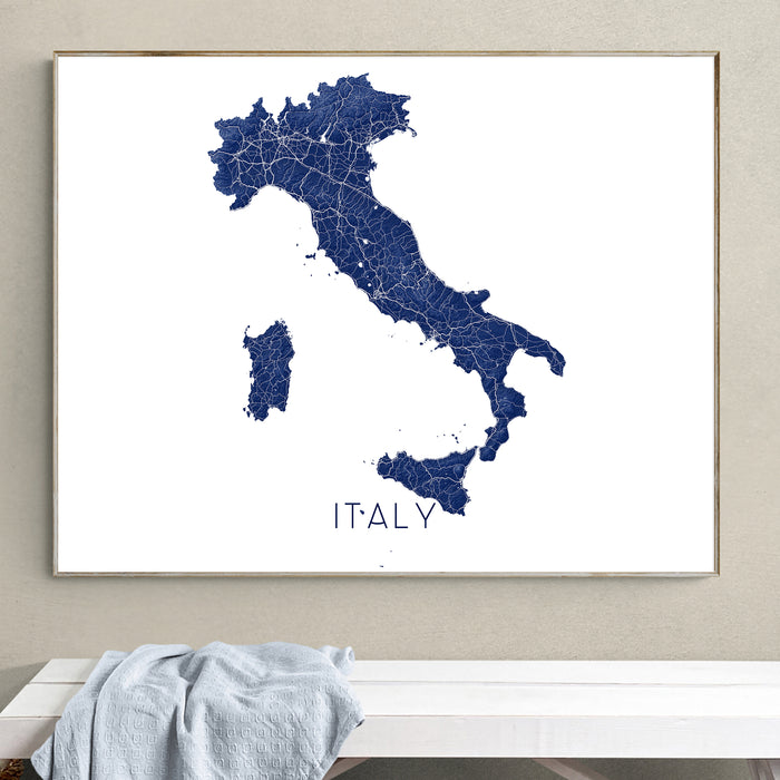 Framed map of Italy on a wall above a white bench.