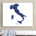 Framed map of Italy on a wall above a white bench.