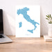 Map of Italy on a desk with a laptop and plant