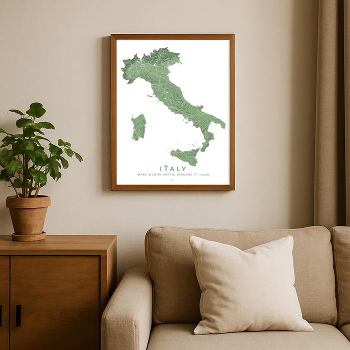 Framed map of Italy on a wall above a sofa with a plant beside it.