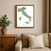 Framed map of Italy on a wall above a sofa with a plant beside it.