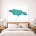 Teal map of Jamaica on a white wall above a bed with wooden headboard.