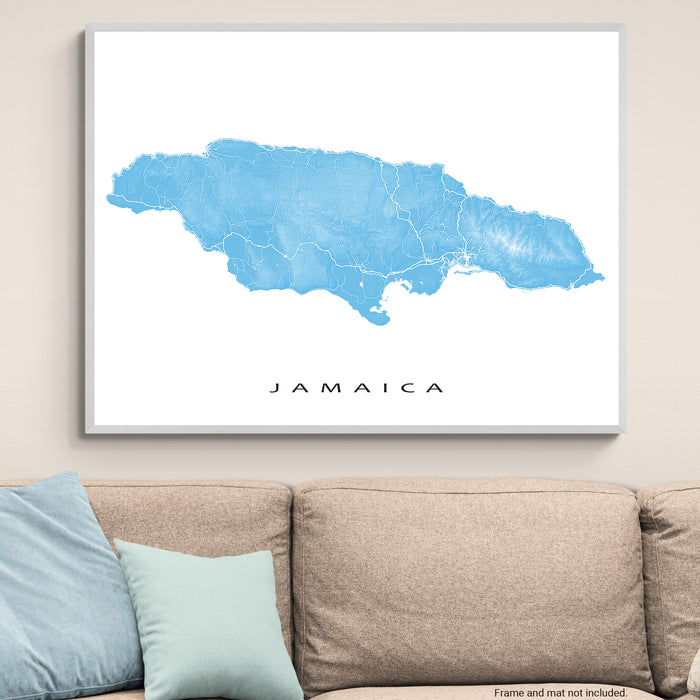 Framed map of Jamaica on a wall above a beige sofa with light blue cushions.
