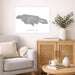 Living room with a map of Jamaica on the wall, a beige armchair, wooden cabinet, and small table.