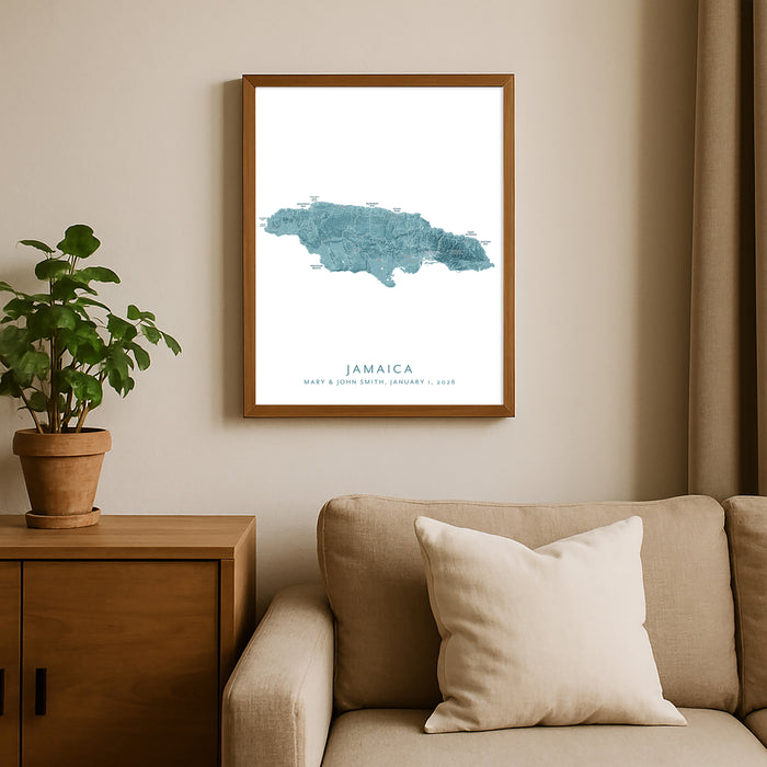Framed map of Jamaica on a wall above a sofa with a plant beside it.