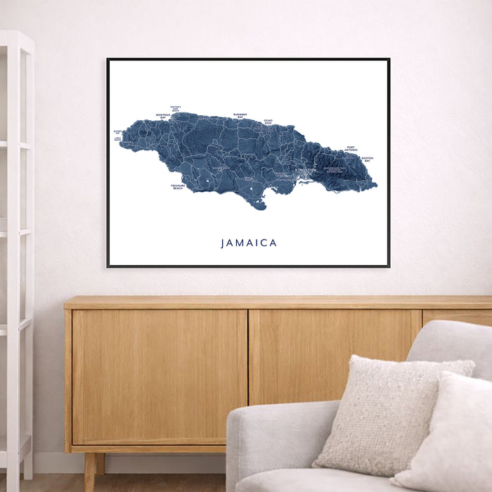 Framed map of Jamaica on a wall above a wooden cabinet and sofa.