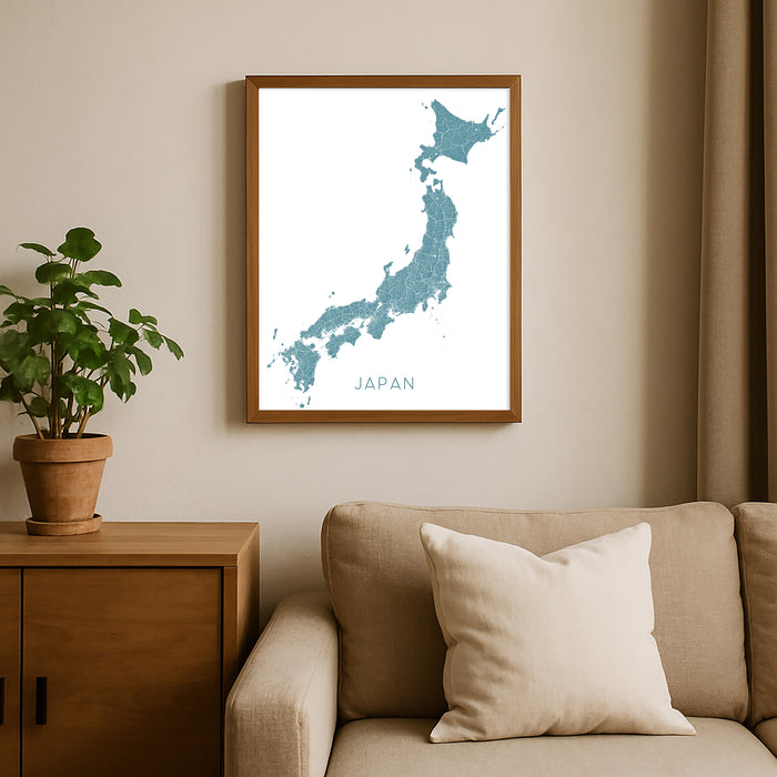 Framed map of Japan on a wall above a beige sofa with a plant beside it.