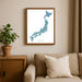 Framed map of Japan on a wall above a beige sofa with a plant beside it.