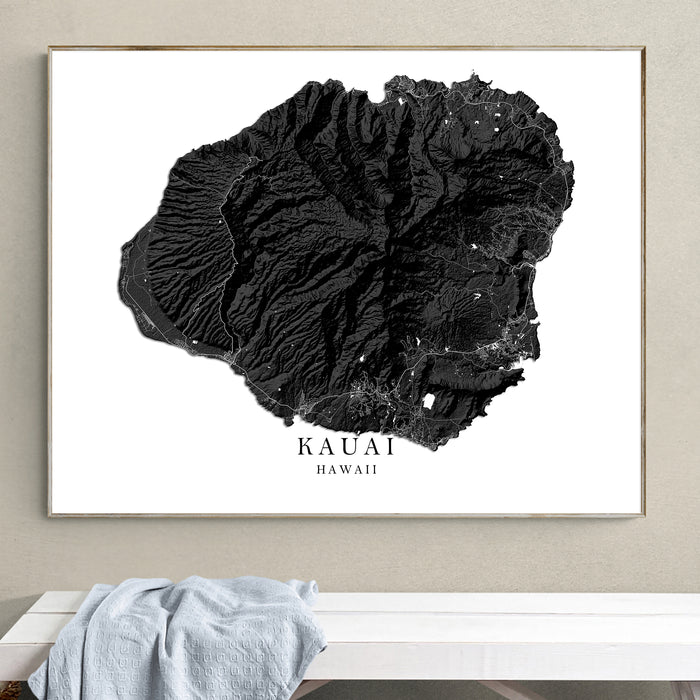Framed black and white topographic map of Kauai, Hawaii on a wall.