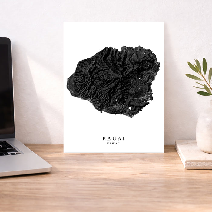 Black coral art print on a white background with 'Kauai Hawaii' text, placed on a wooden desk.