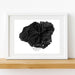 Framed black and white topographic map of Kauai, Hawaii on a wooden shelf.
