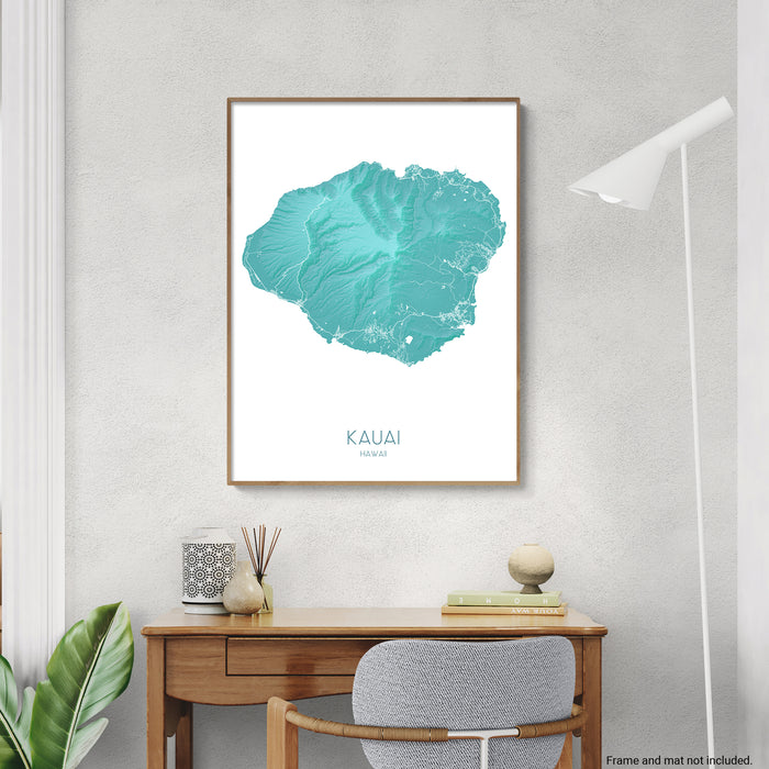 Framed map of Kauai on a wall above a desk with decor items.