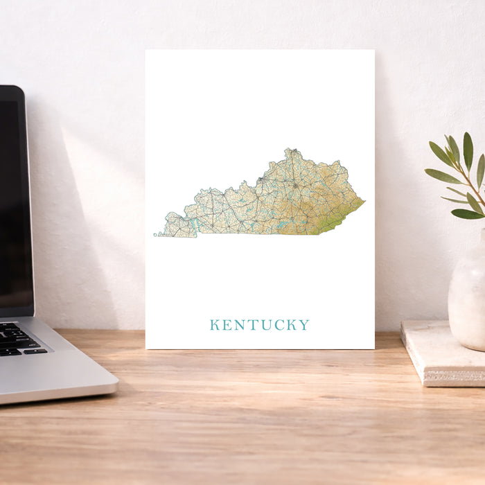 Map of Kentucky on a desk with a laptop and plant