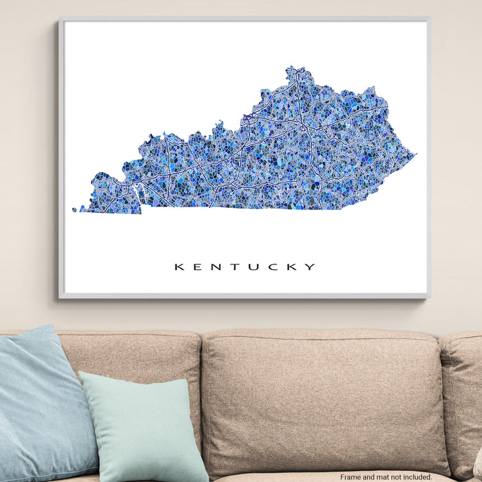 Framed map of Kentucky on a wall above a beige sofa with light blue pillows.