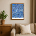 Framed map of London on a wall above a sofa with a plant beside it.