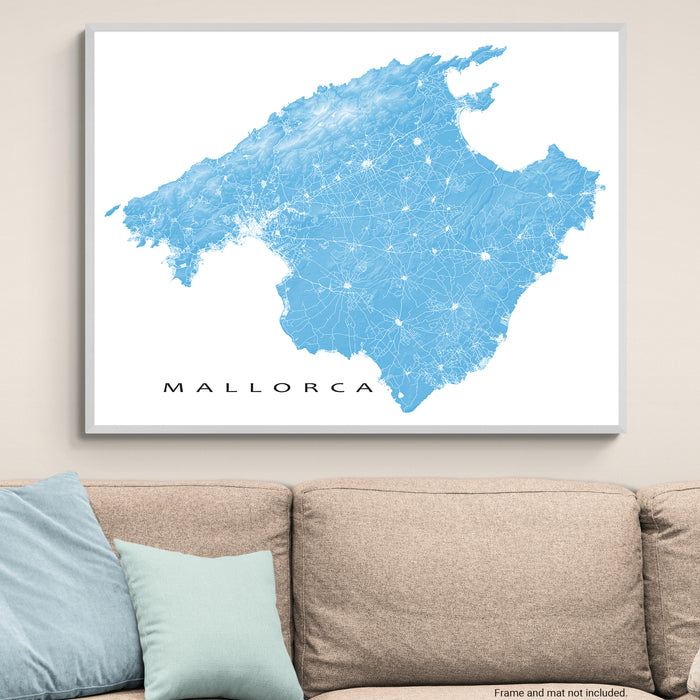 Framed map of Mallorca on a wall above a beige sofa with light blue cushions.