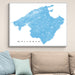 Framed map of Mallorca on a wall above a beige sofa with light blue cushions.