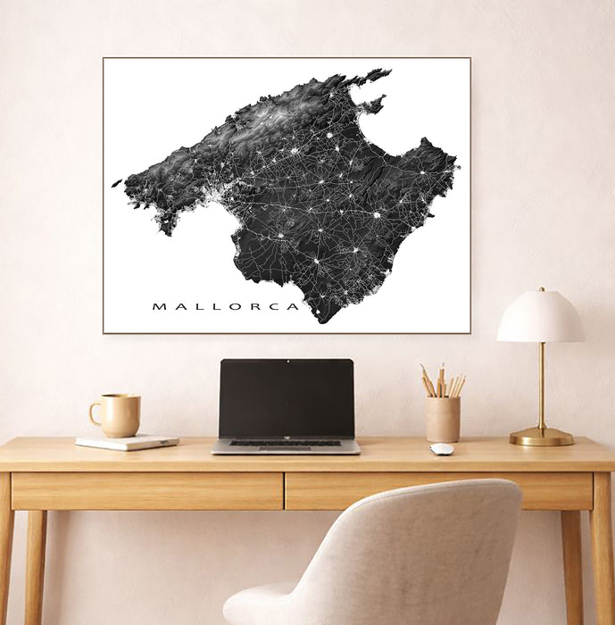 Map of Mallorca on a wall above a desk with a laptop and lamp.