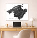 Map of Mallorca on a wall above a desk with a laptop and lamp.