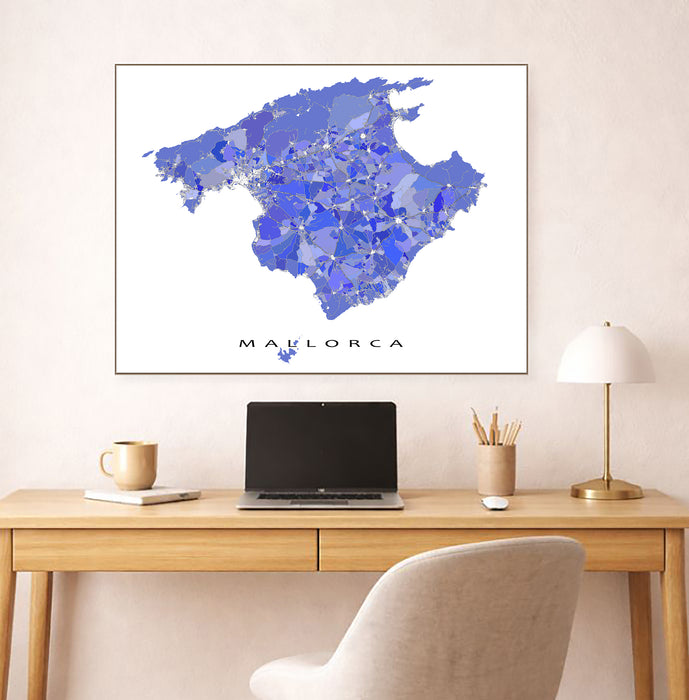 Framed map of Mallorca on a wall above a desk with a laptop and lamp.