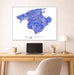 Framed map of Mallorca on a wall above a desk with a laptop and lamp.