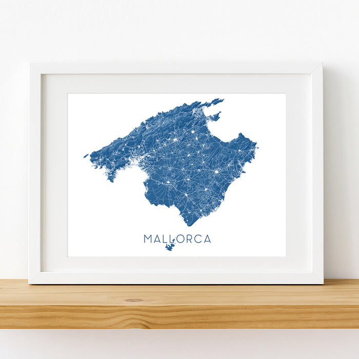 Framed map of Mallorca with blue and white design on a wooden shelf.
