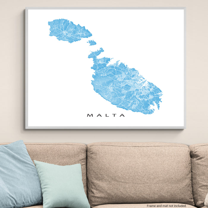Framed map of Malta on a wall above a beige sofa with light blue cushions.